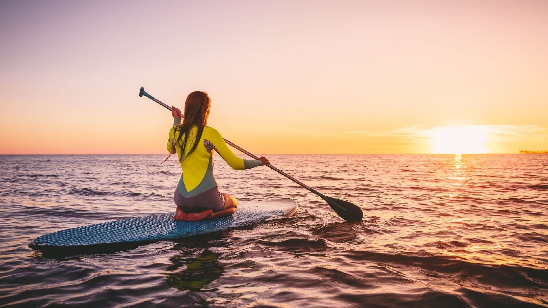 A woman paddleboarding in Panama City Beach during a beautiful sunset